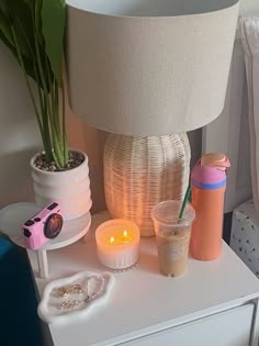 a white table topped with a lamp next to a vase filled with flowers and candles