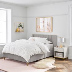 a bedroom with white walls and wooden floors, a bed in the center is surrounded by pink rugs