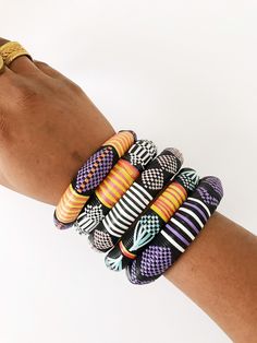 "Beautiful, stylish embroidered bracelets handwoven from recycled plastic by artisans in West Africa. They come in a variety of unique color combinations and patterns, the more you wear, the better. Sizes: Each bracelet is one of a kind and fits wrist size 6-7\". Each is 1/2\" wide with an inside diameter of 2.5-3\" inches. Available in set of 3 or 5. Select as many as you like and enjoy a beautiful arrangement of african colors on your wrist. *The set you select will be the exact set that you w Black Bohemian Bracelets For Festivals, Handmade Black Bohemian Bangle, Traditional Hand Painted Adjustable Bracelets, Multicolor Hand Painted Bangle Bracelets, Traditional Adjustable Purple Bangle, Handmade Bohemian Purple Bangle, Multicolor Hand Painted Bangle Bracelet, Hand Painted Multicolor Bangle Bracelet, Unique Hand Painted Multicolor Bracelets