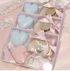 four heart shaped chocolates in a pink box on a table with ribbons and bows