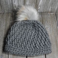 a gray knitted hat with a white fur pom