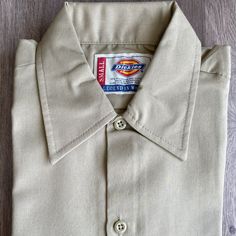 New Dickies Short Sleeve Work-Shirt Regular Fit Flaw: Dirt/Small Mark, Close To The Tag (See Pic) Color: Khaki Size: Small Classic Fitted T-shirt With Button Closure, Fitted Khaki Button-up Shirt, Solid Cotton Dress Shirt With Short Sleeves, Solid Short Sleeve Cotton Dress Shirt, Solid Cotton Short Sleeve Dress Shirt, Fitted Khaki Collared Shirt, Fitted Khaki Casual Shirt, Beige Cotton Top With Spread Collar, Classic Fitted Short Sleeve Shirt With Spread Collar