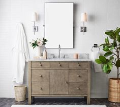 a bathroom with a sink, mirror and potted plant next to it on the floor