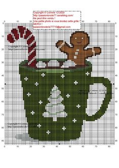 a cross stitch christmas mug with a gingerbread cookie in it and candy canes