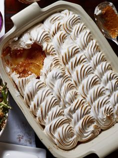 a casserole dish with white frosting on top next to other dishes and utensils