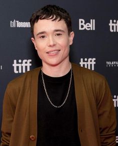 a young man wearing a brown jacket and black shirt