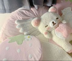 a white teddy bear laying on top of a pink pillow next to a stuffed animal