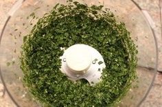 a food processor filled with green vegetables on top of a counter