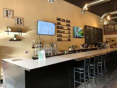 an empty bar with chairs and televisions on the wall