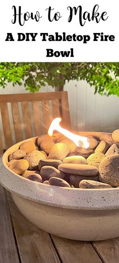 a bowl filled with rocks sitting on top of a wooden table next to a tree