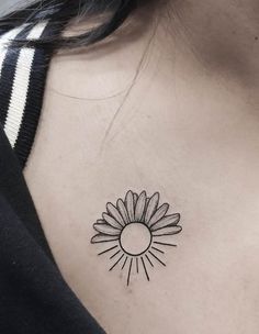 a woman's chest with a small sunflower tattoo on her left side ribcage