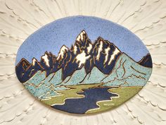 a blue and white plate with mountains in the background on a wall or ceiling decoration