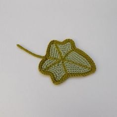 a crocheted leaf is shown on a white surface