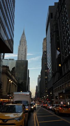 a city street filled with lots of traffic next to tall buildings in the evening time