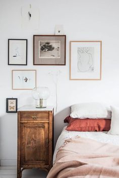 a bedroom with white walls and pictures on the wall