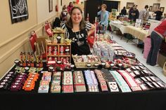 a woman standing in front of a table filled with lots of different types of items