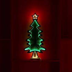 a lit up christmas tree sitting on top of a red shelf next to a wall