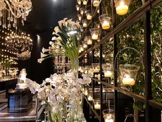 a vase filled with flowers and candles on top of a glass table next to a chandelier