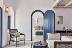 a living room filled with furniture next to a blue door and arched doorway leading into a bedroom