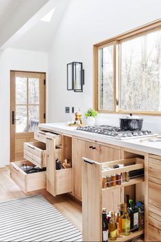 a kitchen with wooden cabinets and white counter tops, drawers under the sink are open