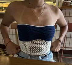 a woman wearing a blue and white top standing in front of a counter with her hands on her hips