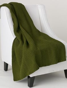 a green blanket sitting on top of a white chair