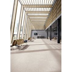 an empty lobby with chairs and wooden slats on the ceiling is seen in this image