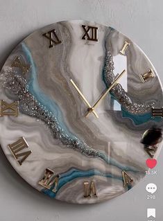 a clock with roman numerals on the face and marbled design in gold