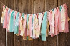 a colorful garland hanging from the side of a wooden fence with ribbons attached to it