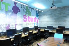 an office with desks and chairs in front of a large mural on the wall