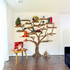 a living room with a christmas tree in the corner and shelves on the wall behind it