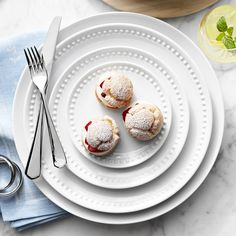 three powdered sugar covered pastries sit on a plate next to a fork and knife