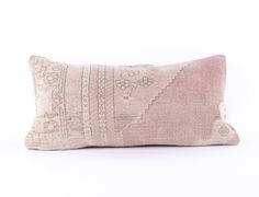 a pink and white pillow with an embroidered design on the front, sitting against a white background