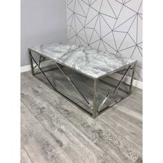 a marble top coffee table with metal frame and geometric pattern on the wall behind it