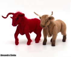 two woolly toy animals standing next to each other on a white surface with one red and the other brown