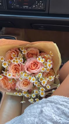 a bouquet of daisies and roses in a woman's lap