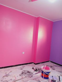 a room that has been painted pink and purple with paintbrushes on the floor