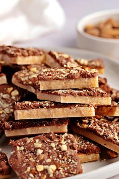 a white plate topped with lots of brownies covered in chocolate and nuts on top of a table