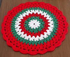 a red and green crocheted doily sitting on top of a wooden table