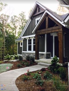 a house that is in the middle of some grass and flowers on the side walk