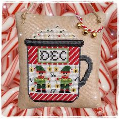 a cross stitch coffee mug on top of candy canes