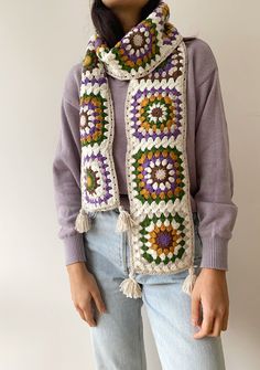 a woman is wearing a crocheted scarf with flowers and fringes on it