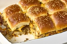 several sliders with cheese and onions in a baking dish on top of a table