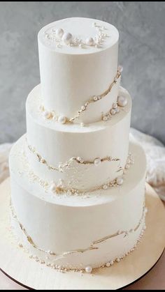 a three tiered white wedding cake with pearls