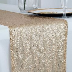 a table topped with a white plate covered in gold sequins next to wine glasses