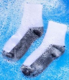 two pairs of socks sitting on top of a blue bathtub filled with water and bubbles