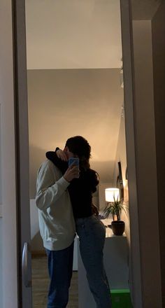 a man and woman standing in front of a mirror taking a selfie with their cell phone