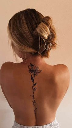 the back of a woman's neck with a flower tattoo on her left side