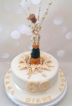 a birthday cake decorated with pearls, beads and a wine bottle on the top tier