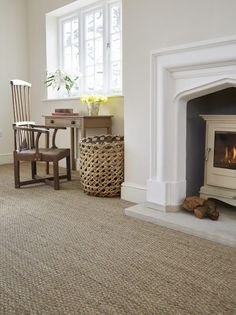 a living room with a fire place next to a chair and table in front of a window